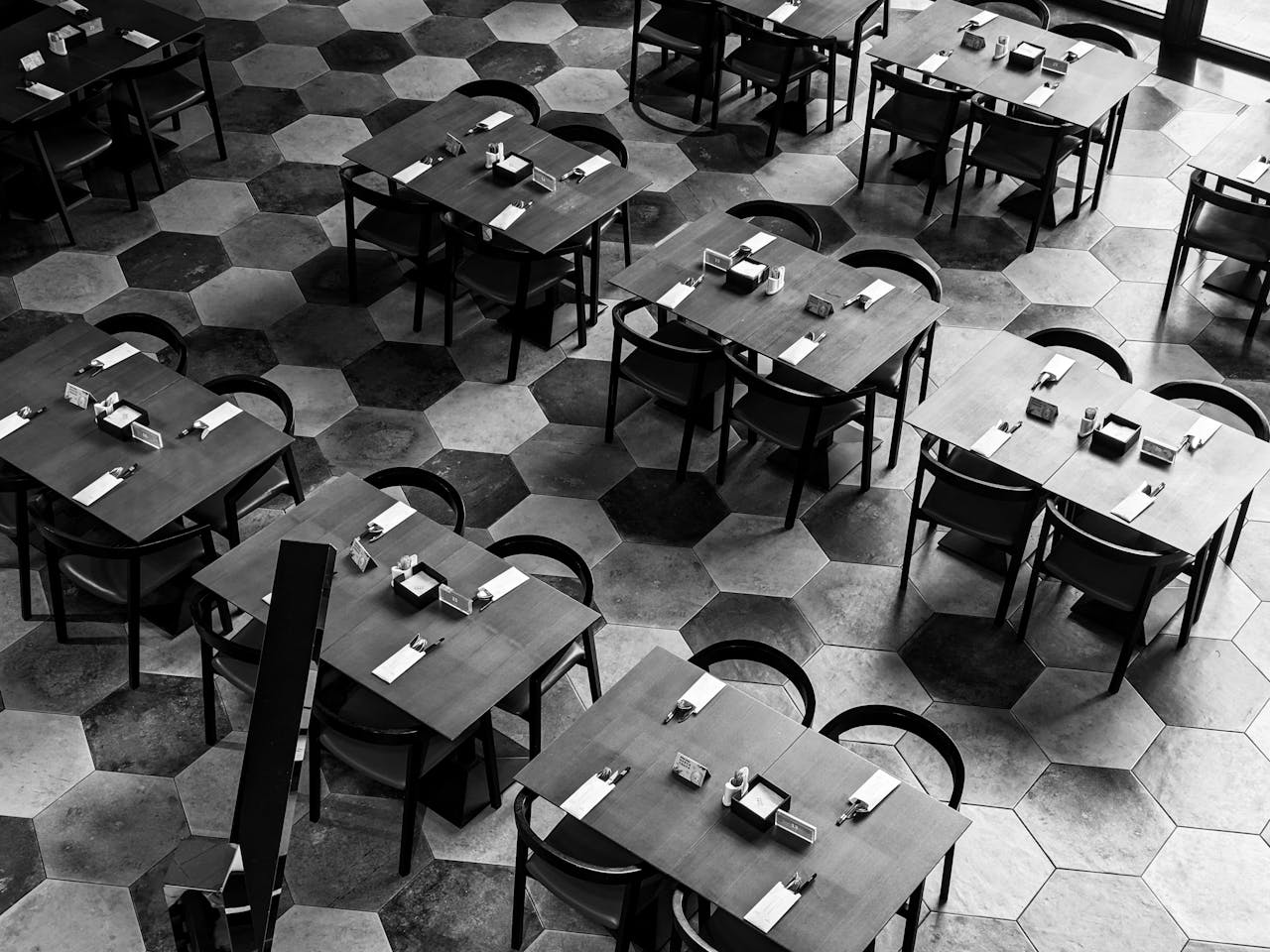 High angle view of empty tables and chairs in a modern restaurant with a hexagonal tile floor.